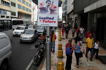 People walk past a banner depicting Venezuela's President Nicolas Maduro that reads "Loyalty and future" in downtown Caracas, Venezuela February 1, 2018. REUTERS/Marco Bello