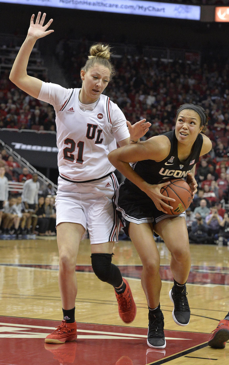 Connecticut forward Kyla Irwin (25) attempts to drive past Louisville forward Kylee Shook (21) during the first half of an NCAA college basketball game in Louisville, Ky., Thursday, Jan. 31, 2019. (AP Photo/Timothy D. Easley)