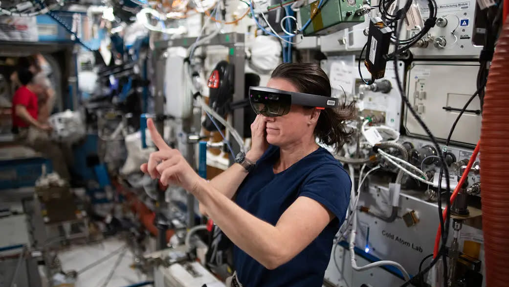  A woman in space wears a vr headset while holding up a finger in the air. 