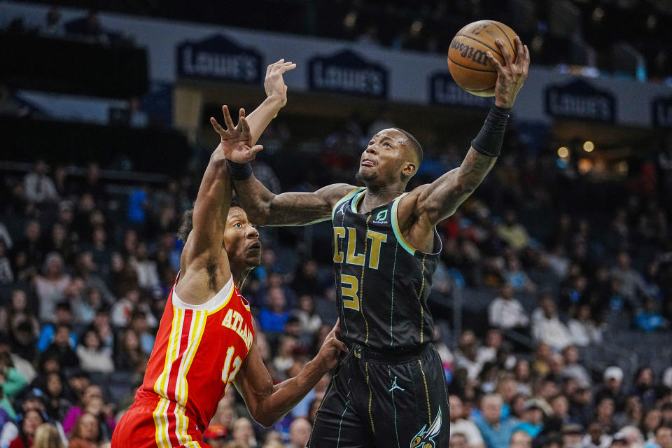 Charlotte Hornets guard Terry Rozier, right, drives into the lane against Atlanta Hawks forward De'Andre Hunter, left, during the first half of an NBA basketball game Friday, Dec. 16, 2022, in Charlotte, N.C. (AP Photo/Rusty Jones)