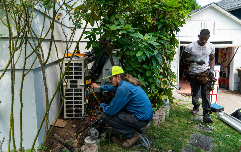 Luke Peters, left, and Elliott Thomas install a mini-split heating and air conditioning system at a home in Seattle on June 23, 2021. A heat wave soon set records across the region.<span class="copyright">Ruth Fremson—The New York Times/Redux</span>