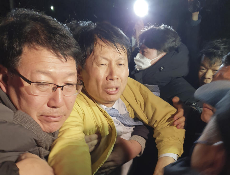 In this Wednesday, Jan. 29, 2020, photo, South Korean Vice Minister of Health and Welfare Kim Gang-lip, second from left, tries to avoid residents as they protest the government's decision to quarantine South Koreans returning from Wuhan in their home town in Jincheon, South Korea. Foreign evacuees from the worst-hit region began returning home under close observation and world health officials expressed "great concern" that the disease is starting to spread between people outside of China. (Jin Sung-hyun/Newsis via AP)