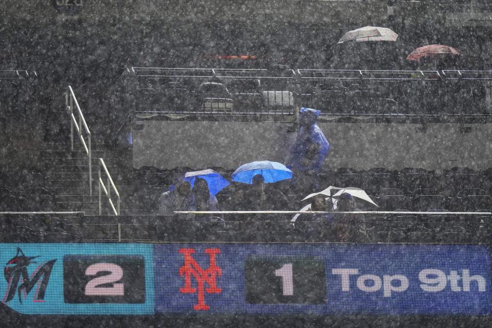 Fans use umbrellas to shield themselves from the rain during a delay in the ninth inning of a baseball game between the New York Mets and the Miami Marlins on Thursday, Sept. 28, 2023, in New York. (AP Photo/Frank Franklin II)