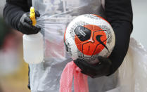 A ball is cleaned by ground staff during the English Premier League soccer match between Burnley and Brighton at the Turf Moor stadium in Burnley, England, Sunday, July 26, 2020. (Alex Livesey/Pool via AP)