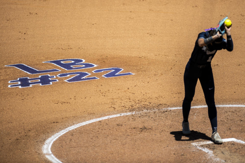 FILE - "LB #22," in honor of James Madison softball catcher Lauren Bernett, is written on the infield behind Liberty pitcher Emily Kirby during an NCAA college softball game against Tennessee at Liberty Softball Stadium in Lynchburg, Va., April 27, 2022. There has been a lot of talk about the mental health struggles that many young athletes face, the pressures and vulnerabilities that can seem overwhelming — especially to those who feel compelled to shield their pain from the outside world. (Kendall Warner/The News & Advance via AP, File)