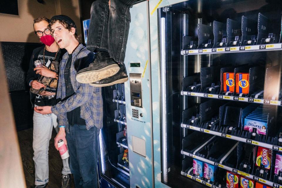 Two people at Laundry Wand stand next to detergent vending machines.