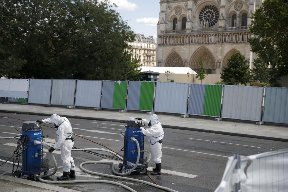 Workers prepare to clean the area in front of Notre Dame cathedral, Monday, Aug. 19, 2019 in Paris. Specialists shoring up fire-damaged Notre Dame Cathedral were returning to the Paris site on Monday for the first time in nearly a month, this time wearing disposable underwear and other protective gear after a delay prompted by fears of lead contamination. (AP Photo/Francois Mori)