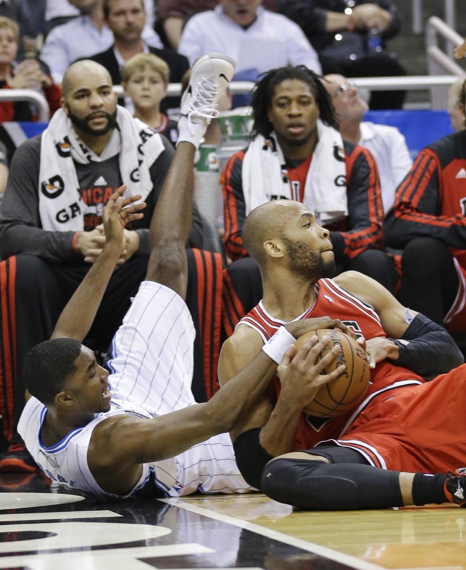 Chicago Bulls' Taj Gibson, right, and Orlando Magic's E'Twaun Moore, left, scramble for a loose ball in front of the Chicago bench during the first half of an NBA basketball game in Orlando, Fla., Wednesday, Jan. 15, 2014. (AP Photo/John Raoux)