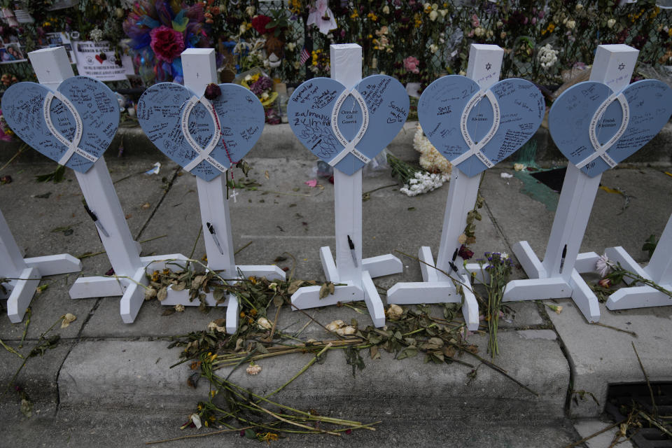 Wilted flowers and messages of love decorate a rain-soaked memorial for the victims of the Champlain Towers South building collapse, on Monday, July 12, 2021, in Surfside, Fla. (AP Photo/Rebecca Blackwell)