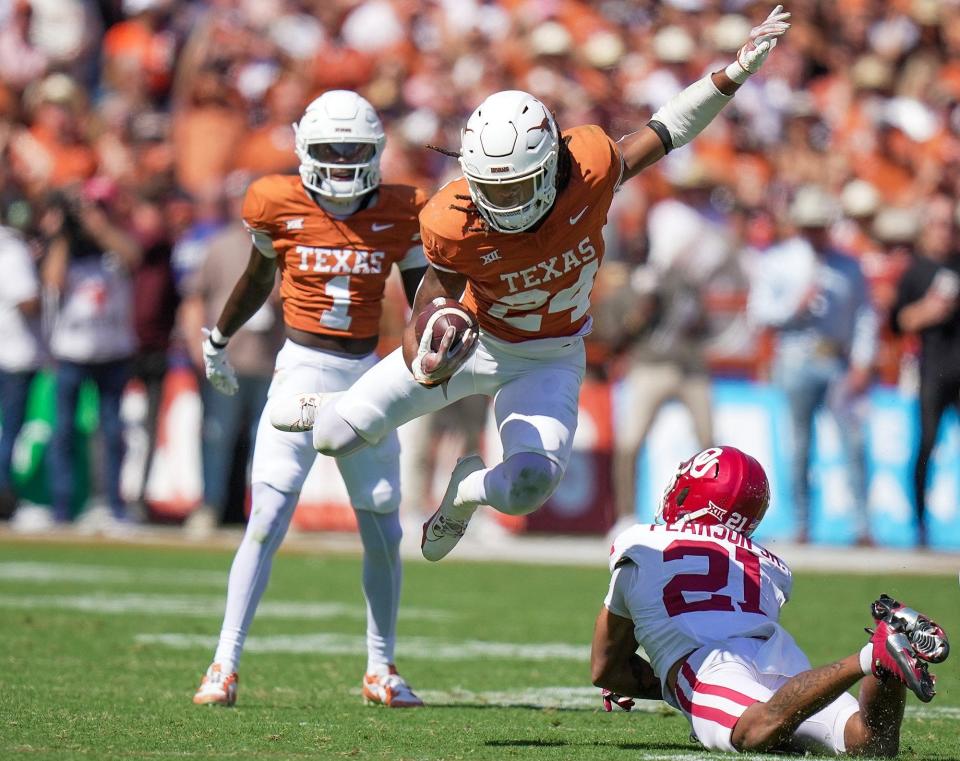 Texas Longhorns running back Jonathon Brooks (24) jumps over Oklahoma Sooners defensive back Reggie Pearson (21) for the first down in the third quarter during an NCAA college football game at the Cotton Bowl on Saturday, Oct. 7, 2023 in Dallas, Texas. This game makes up the119th rivalry match up.