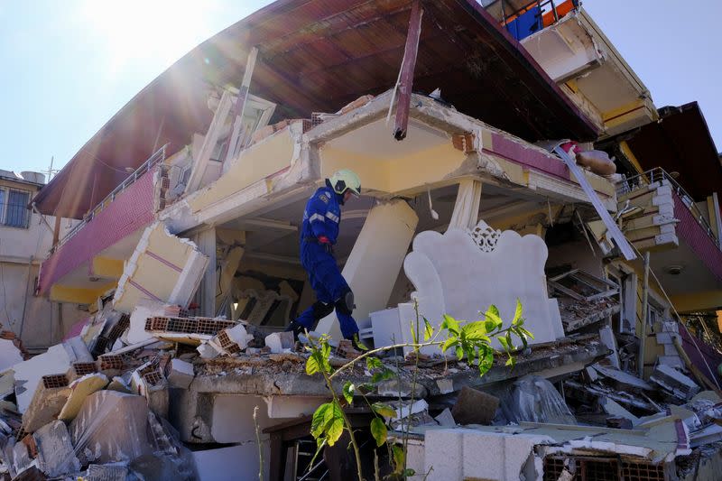Ukrainian rescuer climbs on a demolished home in Hatay, Turkey,