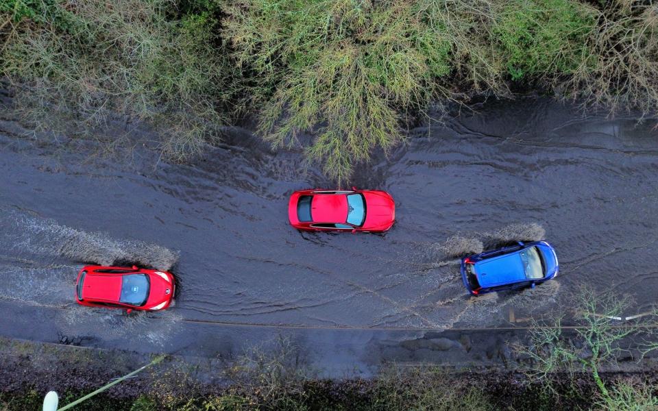 Drivers navigate a stranded car stuck in floodwater near Southampton