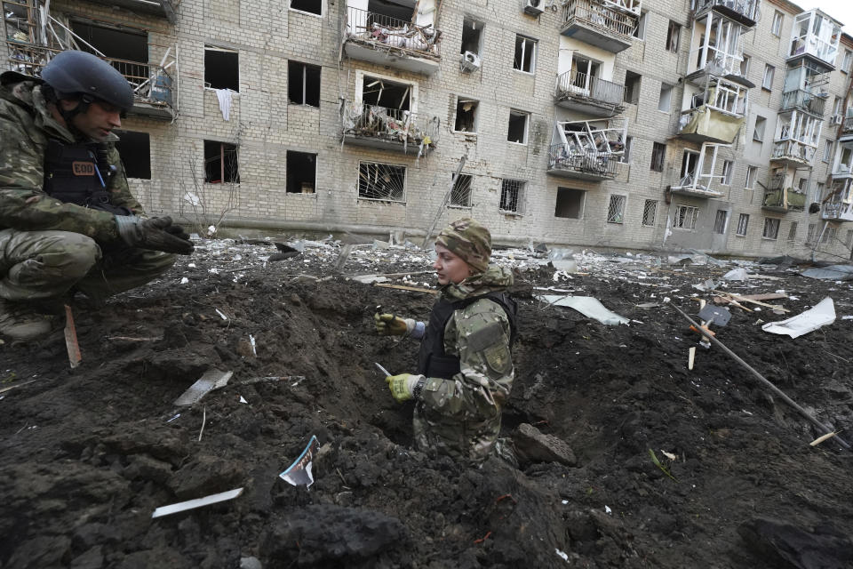 Police officers inspect a crater in front of a damaged residential building hit by a Russian strike in Kharkiv, Ukraine, Wednesday, March 27, 2024. (AP Photo/Andrii Marienko)
