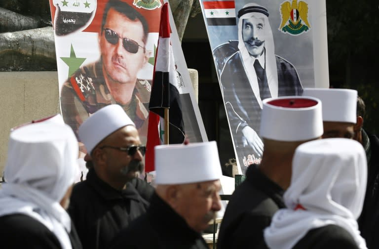 Druze in the Israelio-annexed part of the Golan Heights hold the Syrian flag and portraits of President Bashar al-Assad (C) and late Arab Druze leader Sultan al-Atrash (R) during a rally in the village of Majdal Shams on February 14, 2018