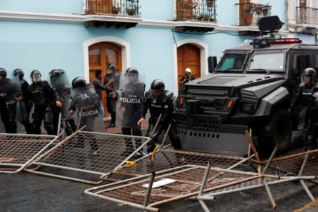 Riot police move barricades during a protest after Ecuadorian President Lenin Moreno's government ended four-decade-old fuel subsidies, in Quito