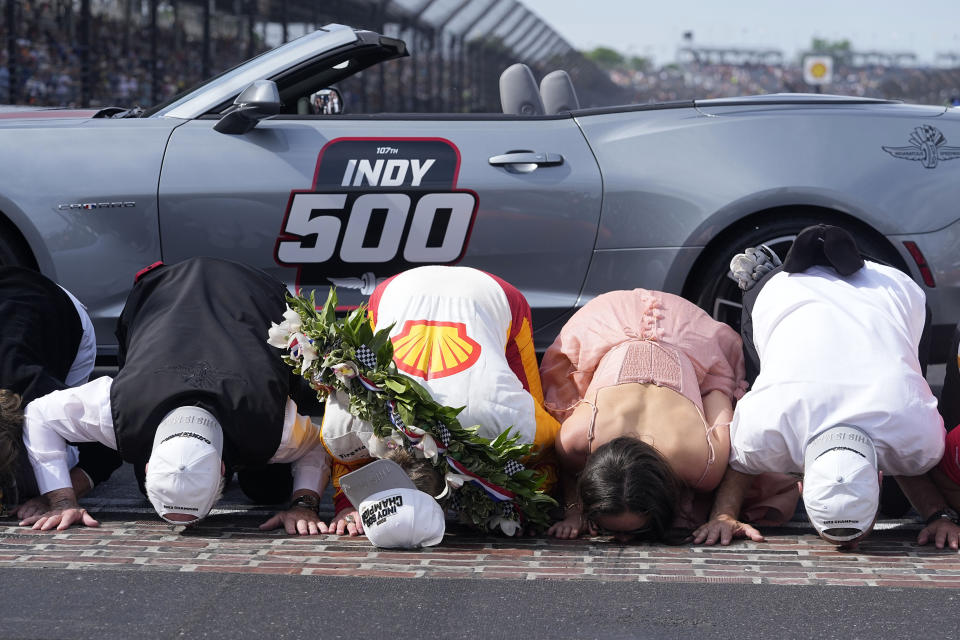 From left to right, Roger Penske, Josef Newgarden, Ashley Newgarden and Tim Cindric kiss the bricks after Josef won the Indianapolis 500 auto race at Indianapolis Motor Speedway, Sunday, May 28, 2023, in Indianapolis. (AP Photo/Darron Cummings)