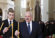 FILE - In this Sunday, April 19, 2020, file photo, Belarusian President Alexander Lukashenko, right, with his son Nikolai, attends the Orthodox Easter service at a church in the village of Malye Lyady outskirts Minsk, Belarus. Belarus’ authoritarian President Alexander Lukashenko faces a perfect storm as he seeks a sixth term in the election held Sunday, Aug. 9, 2020 after 26 years in office. Mounting public discontent over the worsening economy and his government’s bungled handling of the coronavirus pandemic has fueled the largest opposition rallies since the Soviet collapse. (Nikolai Petrov/Pool Photo via AP, File)