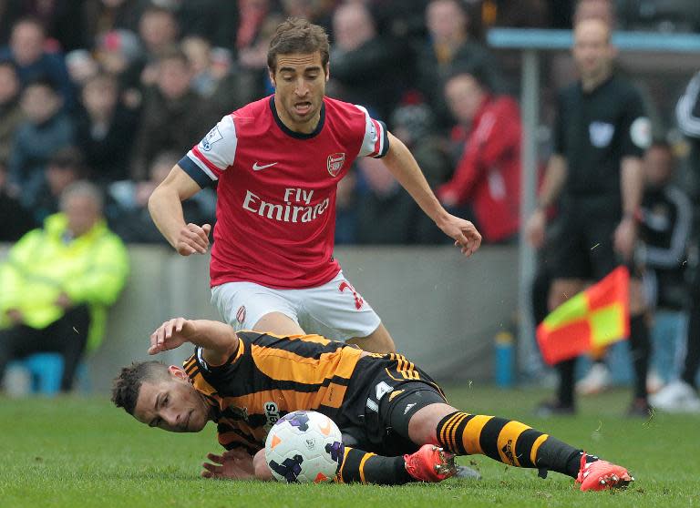 Hull City's Jake Livermore (down) is tackled by Arsenal's Santi Cazorla, at the KC Stadium in Hull, on April 20, 2014