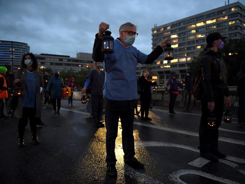 People wearing face masks and holding lanterns attend a vigil for the victims of the coronavirus on Westminster Bridge on 3 July 2020 in London, England: Photo by Chris J Ratcliffe/Getty Images