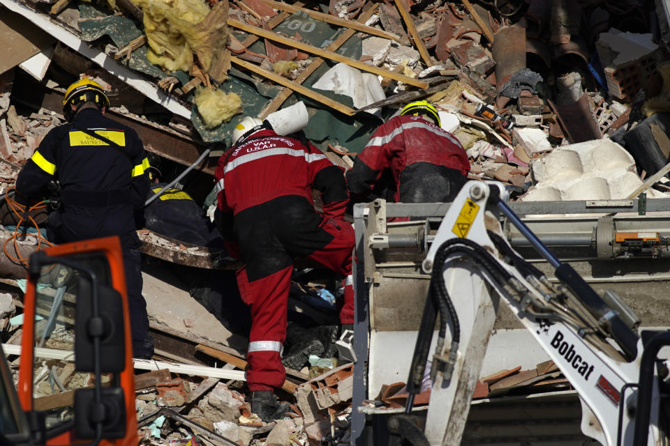 Rescue workers search the rubbles at a three-story apartment building after it collapsed in a suspected gas explosion on southern France's Mediterranean coast, Tuesday, Dec. 7, 2021 in Sanary-sur-Mer. French rescue workers dug out the body of a man but also pulled a toddler and the child's mother alive from the rubble of the building that collapsed in a suspected gas explosion. Two other people are missing. (AP Photo/Daniel Cole)