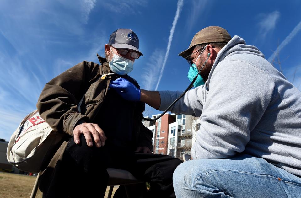 Dr. Pete Cathcart listen to unemployed construction worker Bobby Loyd's heart Dec. 15, 2021, at a pop-up clinic for the homeless in East Nashville in the parking lot of Holy Name Parish Center. "This is heaven for me," Loyd said. "They've helped me out so much."