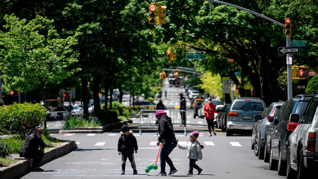 <div>A woman plays with two children on a street, closed to vehicular traffic during a pilot program to provide more space for social distancing amid the novel coronavirus pandemic, on May 13, 2020 in Queens borough of New York City. <strong>(Photo by JOHANNES EISELE/AFP via Getty Images)</strong></div>