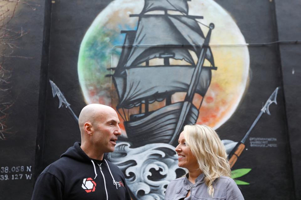 Brad and Jen Cardoza walk past the iconic mural painted outside of the Pour Farm Tavern on Purchase Street in downtown New Bedford.