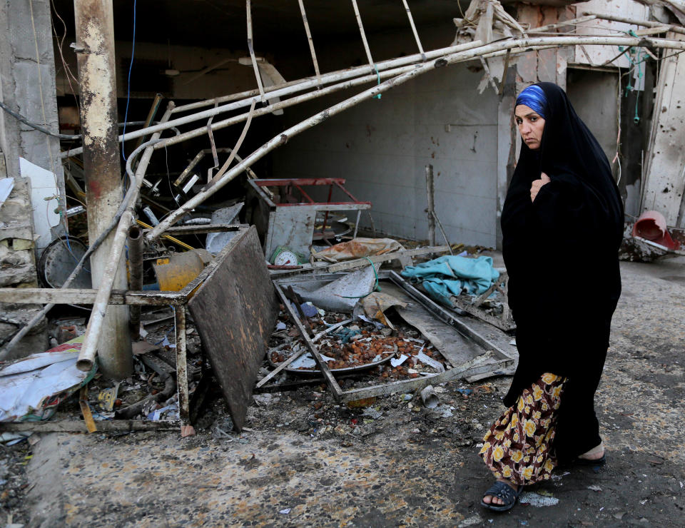 A woman walks past the site of a car bomb attack in the eastern Ur neighborhood of Baghdad, Iraq, Tuesday, Feb. 18, 2014. A wave of explosions rocked mainly Shiite neighborhoods in Baghdad shortly after sunset on Monday, killing and wounding scores of people, said Iraqi officials. (AP Photo/Karim Kadim)