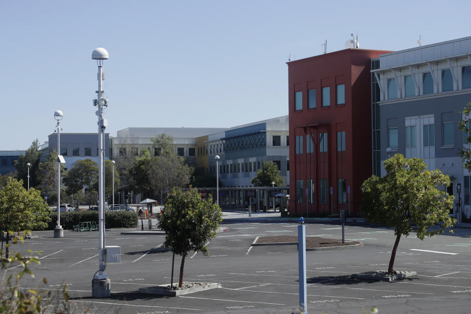 In this Tuesday, April 14, 2020 photo, a nearly empty parking lot is shown on the Facebook campus in Menlo Park, Calif. On the morning of March 15, as Italy became the epicenter of the global coronavirus pandemic, a half dozen high-ranking California health officials held an emergency conference call to discuss a united effort to contain the spread of the virus in the San Francisco Bay Area. That call and the bold decisions that came in the hours afterward have helped California avoid the kind of devastation from the virus in parts of Europe and New York City. (AP Photo/Jeff Chiu)