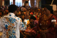 FILE - In this Sunday, Sept. 15, 2013 file photo, T.B. Joshua, left, conducts a service at the Synagogue, Church of All Nations, in Lagos Nigeria. T.B. Joshua's Synagogue, Church of All Nations has branches around the world, and a recent YouTube video even credits him with predicting the disappearance of Malaysian Airlines Flight MH370. Joshua is one of the best-known preachers in Africa and among the most profitable in Nigeria, the go-to faith healer and spiritual guide for leaders such as the late Ghanaian president John Atta Mills, Malawian president Joyce Banda and former Zimbabwean prime minister Morgan Tsvangirai. The man who says he comes from the poor village of Arigidi is worth between $10 and $15 million based on assets, according to Forbes magazine, which in 2011 estimated his personal wealth. The church holds some 15,000 people with outside tents for the overflow and Sunday services are beamed worldwide. Yet critics say this wildly popular televangelist hinders efforts to curtail the spread of HIV and tuberculosis with testimonies by church-goers that faith and his holy water can cure both. He is also accused of taking advantage of his followers and tightly controlling those closest to him, who call him "Daddy."(AP Photo/Carley Petesch, file)