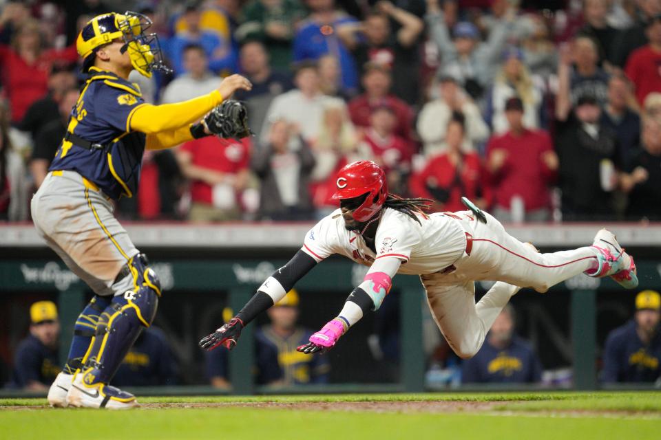Elly De La Cruz of the Cincinnati Reds dives into home plate for an inside-the-park home run in as Brewers catcher William Contreras waits for the throw in the seventh inning Monday night.
