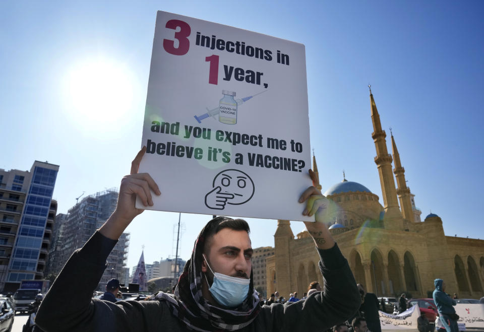 A protester holds a placard during a rally to protest measures imposed against people who are not vaccinated, in Beirut, Lebanon, Saturday, Jan. 8, 2022. Vaccination is not compulsory in Lebanon but in recent days authorities have become more strict in dealing with people who are not inoculated or don’t carry a negative PCR test. (AP Photo/Hussein Malla)