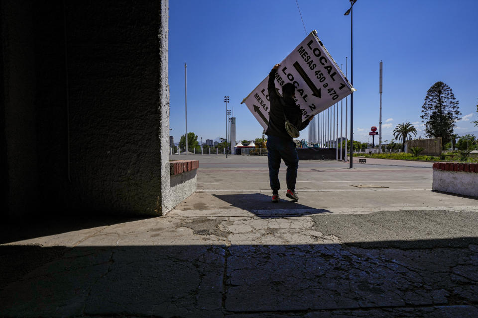 Un empleado electoral carga un cartel informativo en un local de votación montado en el Estadio Nacional, un día antes de un plebiscito constitucional, en Santiago, Chile, el sábado 16 de diciembre de 2023. (AP Foto/Esteban Félix)