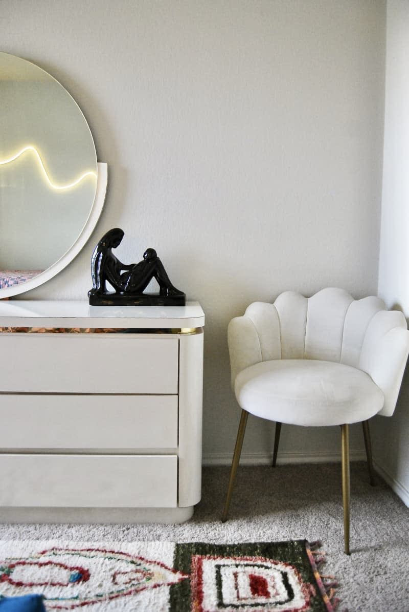 White wavy vanity chair in corner of bedroom.