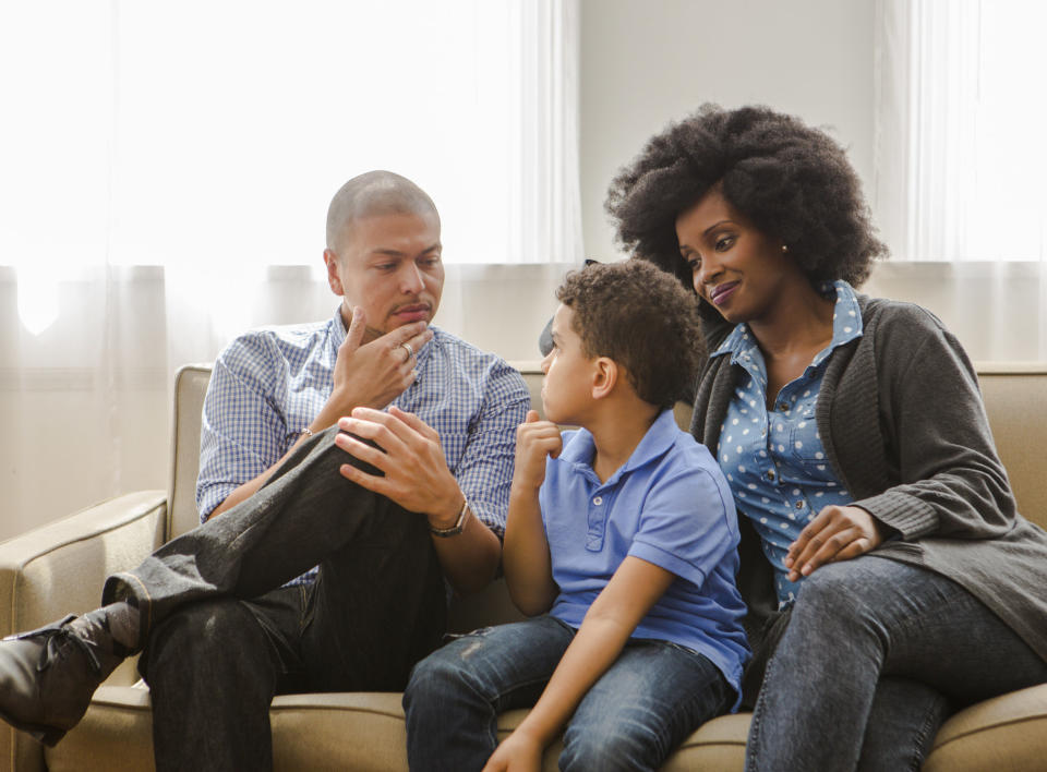 Parents talk to their child on a couch