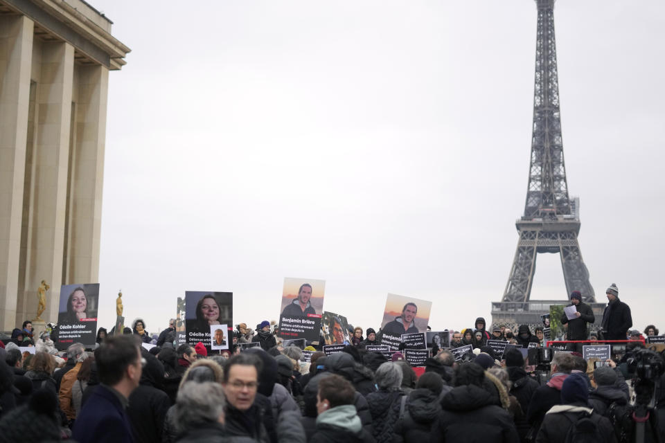 People hold portraits of French hostages in Iran Cecile Kohler, left, and Benjamin Briere during a protest in Paris, Saturday, Jan. 28, 2023. Families and friends of a growing number of Europeans imprisoned in Iran gathered in Paris on Saturday to call for their release. The banner reads : "Freedom for state hostages in Iran". (AP Photo/Thibault Camus)