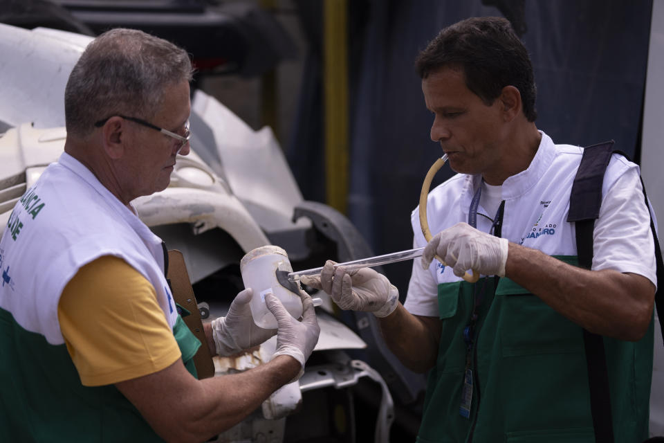 Public health agents capture mosquitoes to take to a lab for analysis, at a scrapyard in Nova Iguacu, Rio de Janeiro state, Brazil, Tuesday, Feb. 6, 2024. Cities around Brazil, including Rio, have declared a public health emergency related to an outbreak of dengue fever just days ahead Carnival. (AP Photo/Silvia Izquierdo)