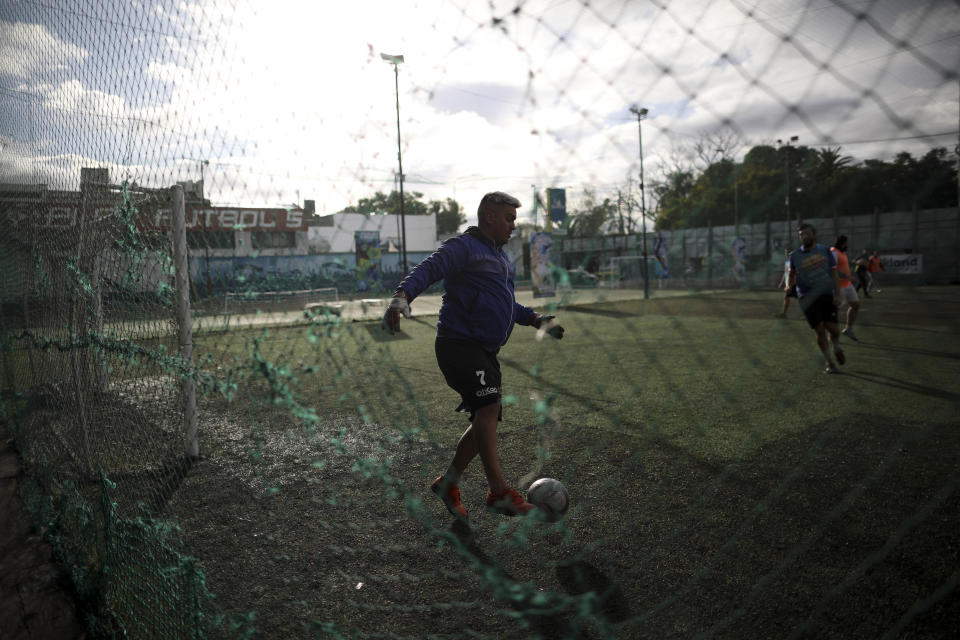 Martin Rodriguez controls the ball during an amateur soccer match at the Play Futbol 5 local club in Pergamino, Argentina, Wednesday, July 1, 2020. In order to continue playing amid government restrictions to curb the spread of the new coronavirus, the club divided its soccer field into 12 rectangles to mark limited areas for each player, keeping them from making physical contact. (AP Photo/Natacha Pisarenko)