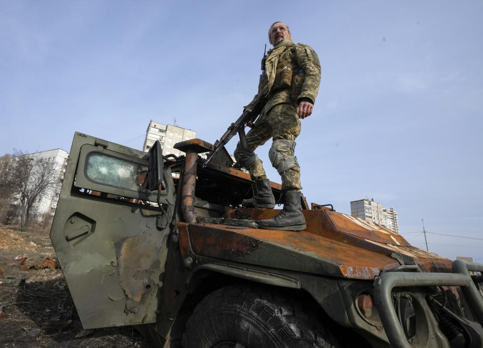 FILE - A Ukrainian soldier stands a top a destroyed Russian APC after recent battle in Kharkiv, Ukraine, on March 26, 2022. With Russia continuing to strike and encircle urban populations, from Chernihiv and Kharkiv in the north to Mariupol in the south, Ukrainian authorities said Saturday that they cannot trust statements from the Russian military Friday suggesting that the Kremlin planned to concentrate its remaining strength on wresting the entirety of Ukraine's eastern Donbas region from Ukrainian control. (AP Photo/Efrem Lukatsky)