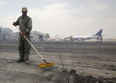 A man clears debris from the tarmac of Jinnah International Airport, after the attack by Taliban militants on Sunday, in Karachi in this June 10, 2014 file photo. REUTERS/Athar Hussain/Files