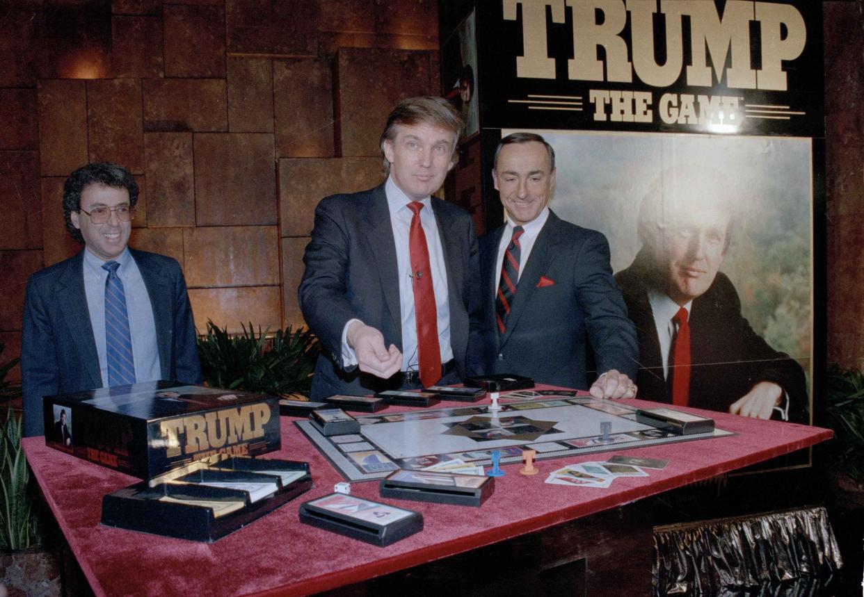 Real estate mogul Donald Trump, left, takes his turn as George Ditomassi, president of the Milton Bradley company, looks on at a news conference in New York, announcing a new board game, 