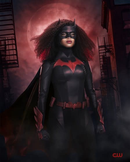 A woman wearing a black bodysuit with a red bat logo, a mask and cape