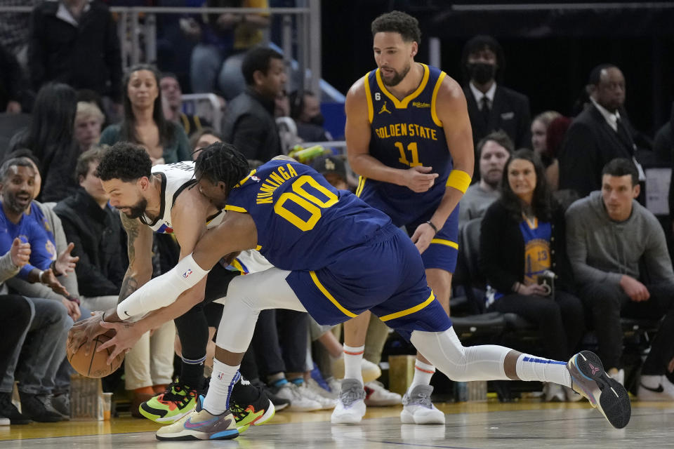 Golden State Warriors forward Jonathan Kuminga (00) reaches for the ball against Minnesota Timberwolves guard Austin Rivers, left, as Klay Thompson (11) watches during the first half of an NBA basketball game in San Francisco, Sunday, Feb. 26, 2023. (AP Photo/Jeff Chiu)