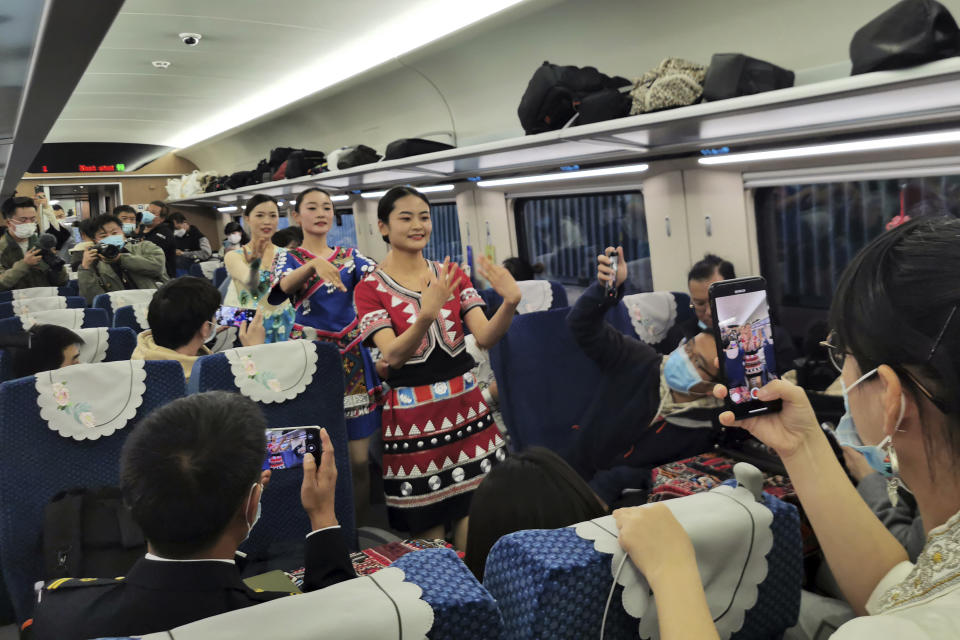 FILE - Women in ethnic dresses perform on a passenger carriage of the first regular train service on the Chinese section of the railway between Kunming and Vientiane, the Laotian capital, after its debut ceremony in Kunming in southwestern China's Yunnan province, on Dec. 3, 2021. The railway is one of hundreds of projects under Beijing's Belt and Road Initiative to build ports, railways and other facilities across Asia, Africa and the Pacific. (Chinatopix via AP, File)