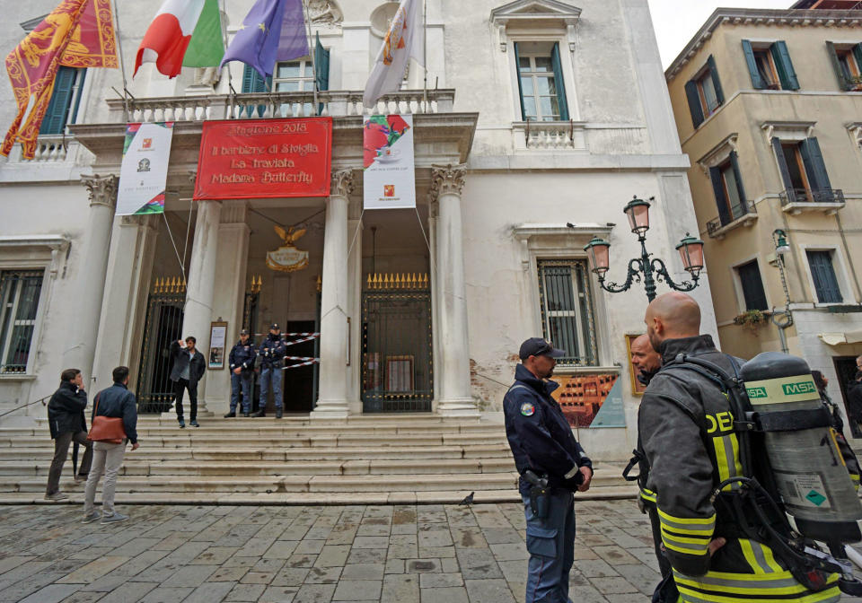 Firefighters and police officers stand outside La Fenice opera house after a fire apparently broke out in a technical room, in Venice, Italy, Monday, Oct. 1, 2018. According to agencies a fire has been brought swiftly under control in Venice's La Fenice opera house, which was rebuilt after being destroyed by flames in 1996. (Andrea Merola/ANSA via AP)