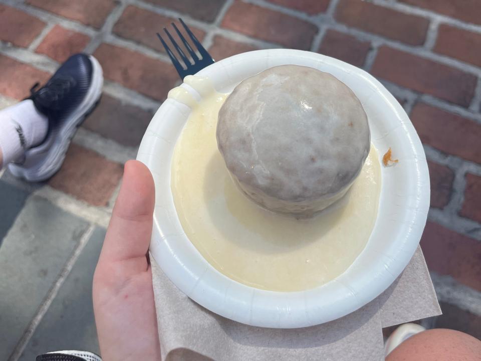 hand holding a plate of carrot cake covered in icing at epcot in disney world