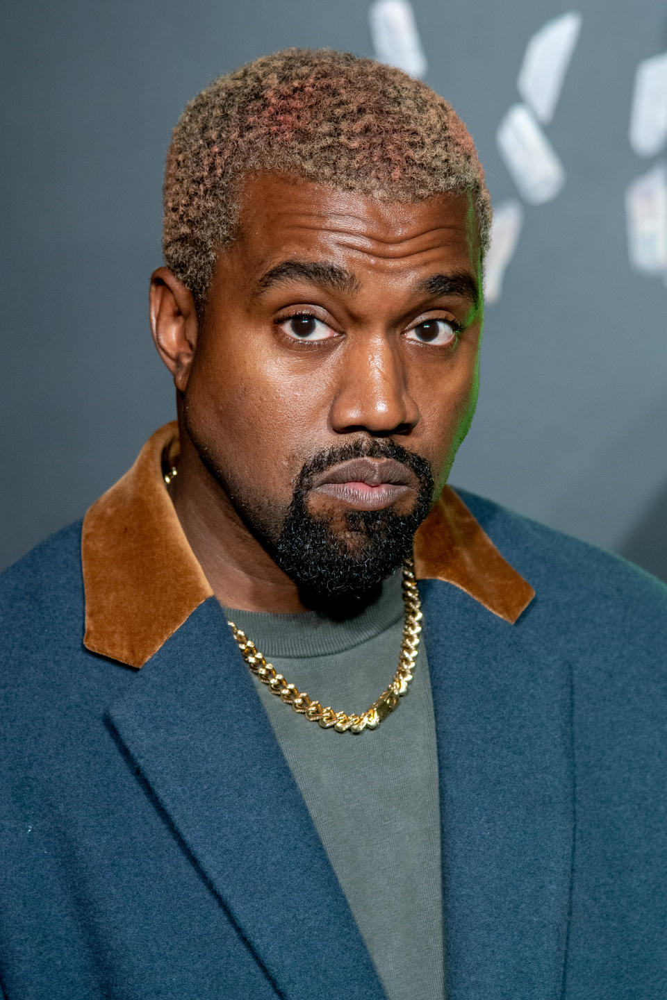 American rapper Kanye West posing for picture wearing teal jacket 