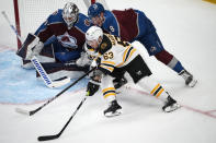 Boston Bruins left wing Brad Marchand, front, wraps around the net past Colorado Avalanche defenseman Cale Makar, center, to put a shot on goaltender Alexandar Georgiev during the first period of an NHL hockey game Wednesday, Dec. 7, 2022, in Denver. (AP Photo/David Zalubowski)