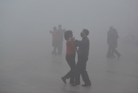 People wearing masks dance at a square among heavy smog during a polluted day in Fuyang, Anhui province, China, January 3, 2017. China Daily/via REUTERS