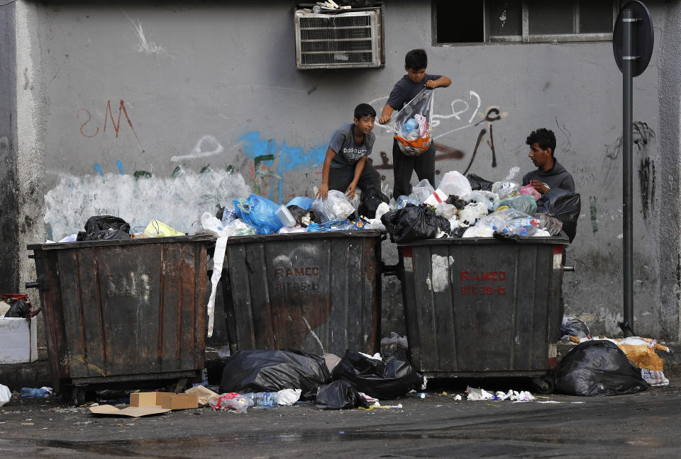 FILE - Boys scavenge in garbage dumpsters for valuables and metal cans to sell, in Beirut, Lebanon, June 17, 2021. As Lebanon faces one of the world’s worst financial crises in modern history, now even its trash has become a commodity fought over in the street. (AP Photo/Hussein Malla, File)